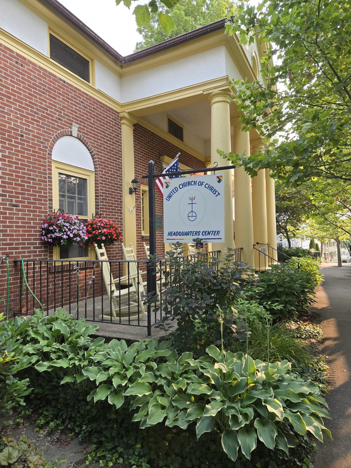 A red brick house with white columns and a sign for the United Church of Christ Headquarters